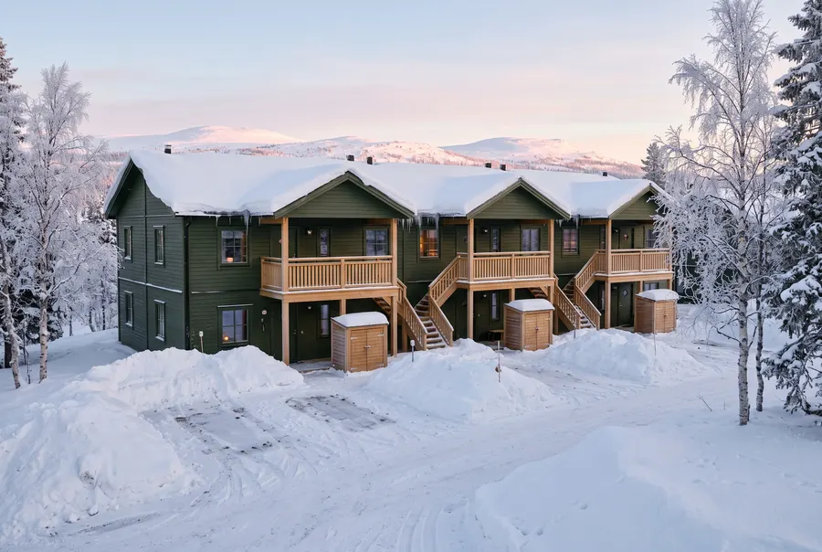 Exempelbild: grönt radhus i två våningar med balkonger, i snön vid fjället