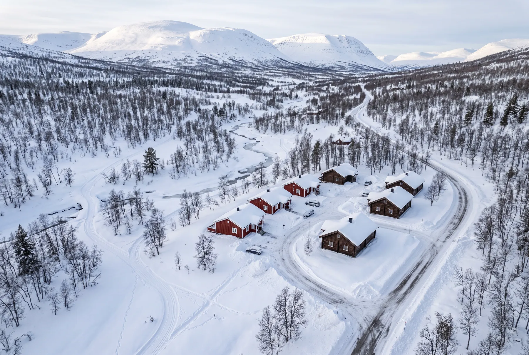 Exempelbild: liten stugby i snön sedd från ovan, med fjällen i bakgrunden